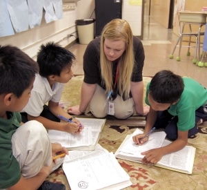 Woman Teaching Boys with Text Books On Floor